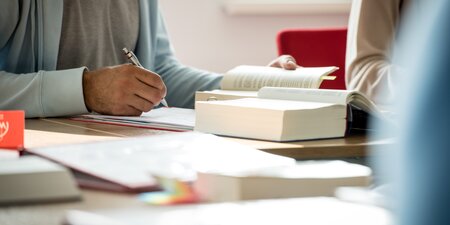Eine Person schreibt etwas auf ein Blattpapier Eine Person schreibt etwas auf ein Blattpapier
