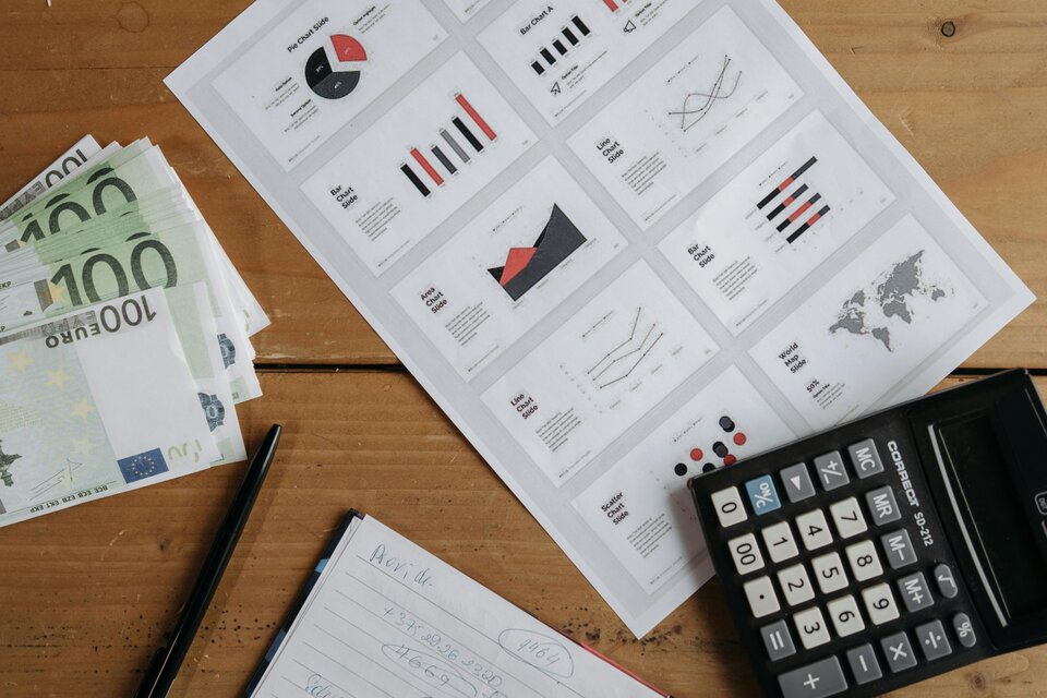 Tisch mit Geldscheinen, Taschenrechner, Diagrammen und Notizen – Symbolbild für betriebliche Entlohnungsgrundsätze und Mitbestimmung des Betriebsrats bei der Lohngestaltung. Tisch mit Geldscheinen, Taschenrechner, Diagrammen und Notizen – Symbolbild für betriebliche Entlohnungsgrundsätze und Mitbestimmung des Betriebsrats bei der Lohngestaltung.