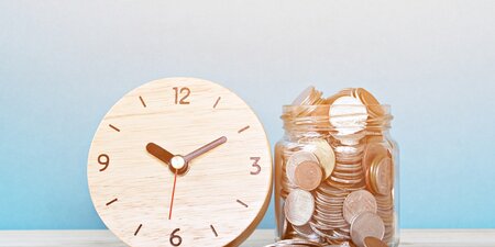 Eine Uhr und ein Glas voller Münzen symbolisieren die enge Verbindung von Zeit und Geld – zentrale Themen in der Diskussion über faire Bezahlung von Menschen mit Behinderung. Eine Uhr und ein Glas voller Münzen symbolisieren die enge Verbindung von Zeit und Geld – zentrale Themen in der Diskussion über faire Bezahlung von Menschen mit Behinderung.