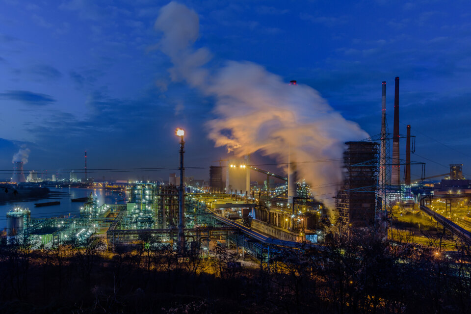 Ein Industriegebiet bei Nacht mit rauchenden Schornsteinen und beleuchteten Werksanlagen – das Bild symbolisiert die wirtschaftliche Krise und die Herausforderungen für Betriebsräte in Zeiten von Stellenabbau. Ein Industriegebiet bei Nacht mit rauchenden Schornsteinen und beleuchteten Werksanlagen – das Bild symbolisiert die wirtschaftliche Krise und die Herausforderungen für Betriebsräte in Zeiten von Stellenabbau.