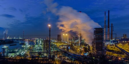 Ein Industriegebiet bei Nacht mit rauchenden Schornsteinen und beleuchteten Werksanlagen – das Bild symbolisiert die wirtschaftliche Krise und die Herausforderungen für Betriebsräte in Zeiten von Stellenabbau. Ein Industriegebiet bei Nacht mit rauchenden Schornsteinen und beleuchteten Werksanlagen – das Bild symbolisiert die wirtschaftliche Krise und die Herausforderungen für Betriebsräte in Zeiten von Stellenabbau.