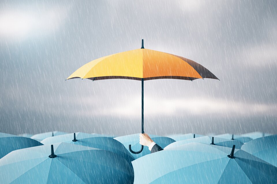 Ein gelber Regenschirm sticht bei Regenwetter aus einer Menge blauer Schirme hervor – Symbol für den besonderen Schutz (schwer-)behinderter Menschen bei Betriebsänderungen. Title: Ein gelber Regenschirm sticht bei Regenwetter aus einer Menge blauer Schirme hervor – Symbol für den besonderen Schutz (schwer-)behinderter Menschen bei Betriebsänderungen. Title:
