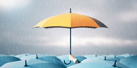 Ein gelber Regenschirm sticht bei Regenwetter aus einer Menge blauer Schirme hervor – Symbol für den besonderen Schutz (schwer-)behinderter Menschen bei Betriebsänderungen. Title: Ein gelber Regenschirm sticht bei Regenwetter aus einer Menge blauer Schirme hervor – Symbol für den besonderen Schutz (schwer-)behinderter Menschen bei Betriebsänderungen. Title: