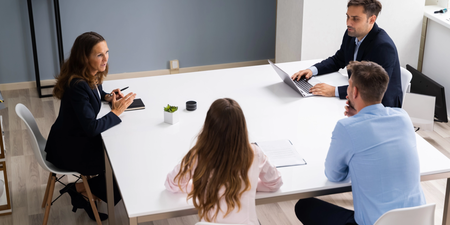 Vier Personen sitzen an einem Besprechungstisch in einem modernen Büro und führen ein Gespräch.