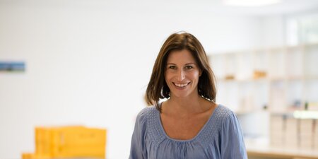 Eine Frau hat Bücher in der Hand und schaut in die Kamera Eine Frau hat Bücher in der Hand und schaut in die Kamera