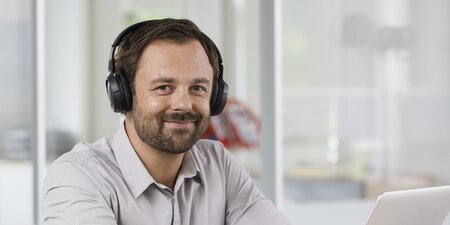 Ein Mann sitzt vor einem Laptop und arbeitet Ein Mann sitzt vor einem Laptop und arbeitet