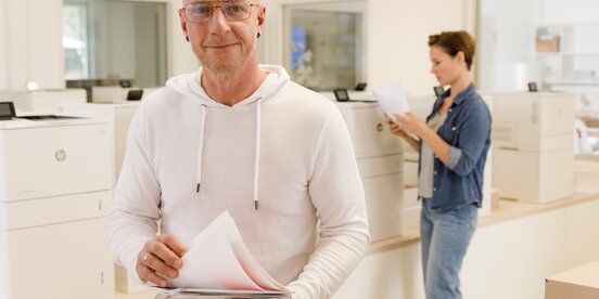 Ein Mann hat gedrucktes Papier in der Hand
