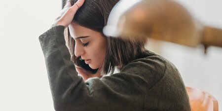 Eine Frau ist krank und fasst sich am Kopf Eine Frau ist krank und fasst sich am Kopf
