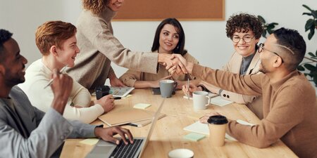 Ein fröhliches Team in einem Meetingraum, zwei Personen geben sich zur Begrüßung die Hand – das Bild symbolisiert gelungene Zusammenarbeit und erfolgreiche Klausurtagung im Betriebsrat. Ein fröhliches Team in einem Meetingraum, zwei Personen geben sich zur Begrüßung die Hand – das Bild symbolisiert gelungene Zusammenarbeit und erfolgreiche Klausurtagung im Betriebsrat.