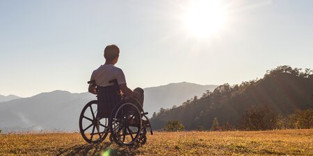 Ein Mann im Rollstuhl genießt die Aussicht auf ein sonniges Bergpanorama – Symbol für barrierefreies Reisen und Inklusion im Tourismus. Ein Mann im Rollstuhl genießt die Aussicht auf ein sonniges Bergpanorama – Symbol für barrierefreies Reisen und Inklusion im Tourismus.