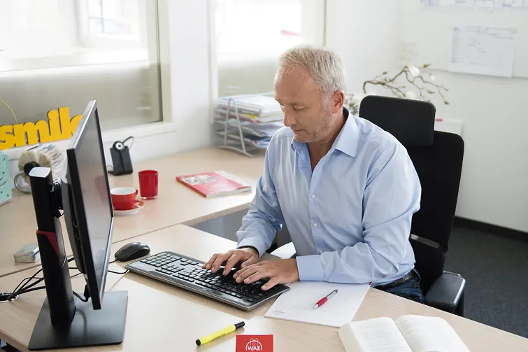 Mann trägt seine Arbeitszeit in den Computer ein Mann trägt seine Arbeitszeit in den Computer ein