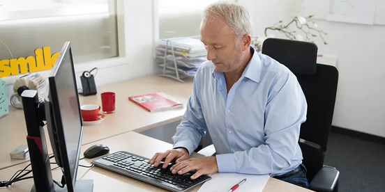 Mann trägt seine Arbeitszeit in den Computer ein Mann trägt seine Arbeitszeit in den Computer ein