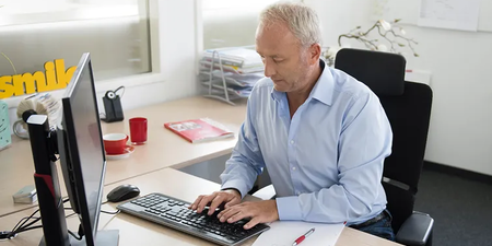 Mann trägt seine Arbeitszeit in den Computer ein Mann trägt seine Arbeitszeit in den Computer ein