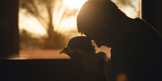 Ein Mann hält sein Baby in den Armen