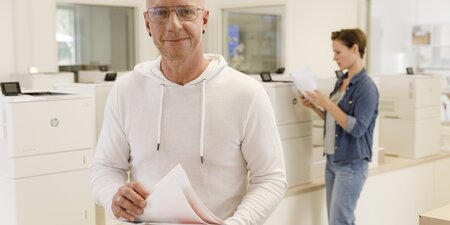 Ein Mann steht vor einem Drucker