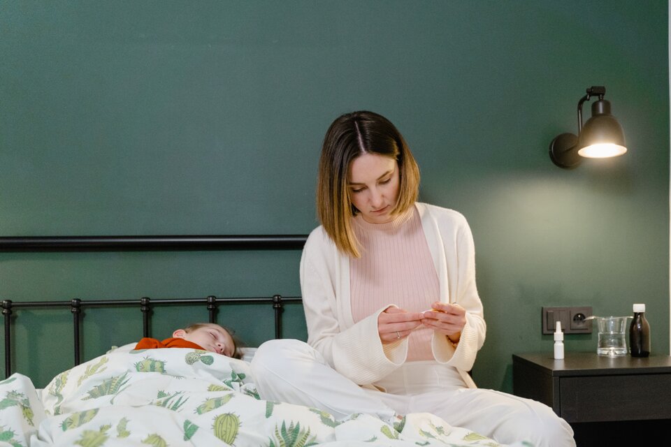 Kind liegt Krank im Bett und Mutter passt auf Kind liegt Krank im Bett und Mutter passt auf