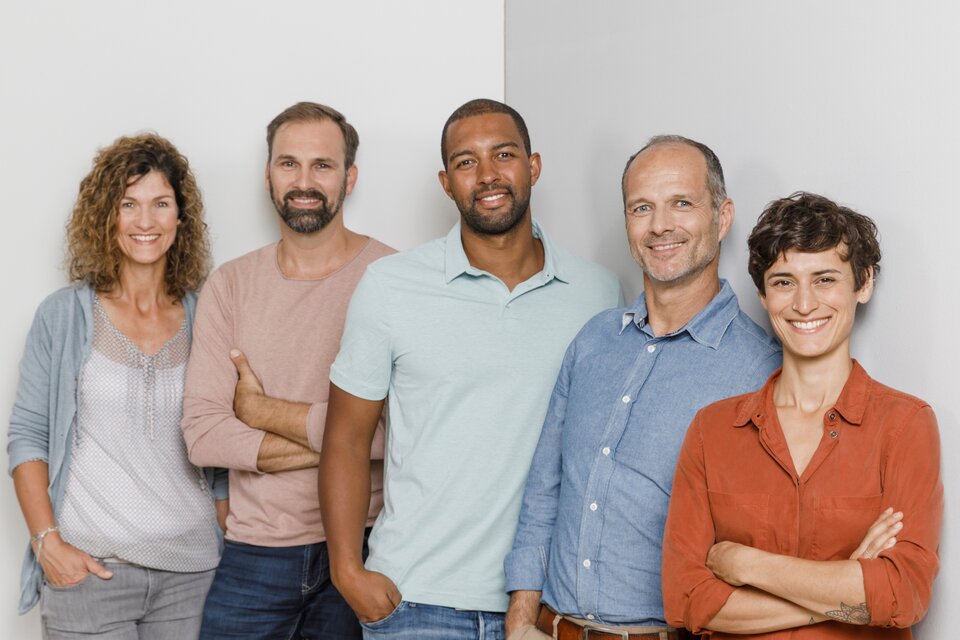 Fünf Kollegen stehen vor einer grauen Wand Fünf Kollegen stehen vor einer grauen Wand
