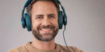 Ein Mann schaut in die Kamera und trägt ein Headset Ein Mann schaut in die Kamera und trägt ein Headset