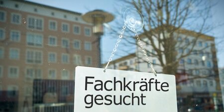 An einem Fenster ein Schild auf dem steht: Fachkräfte gesucht