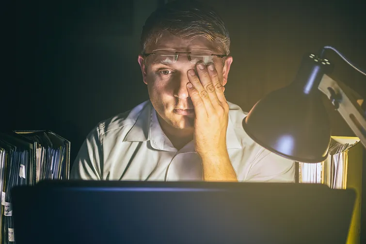 Mann sitzt spät abends verzweifelt vor seinem Laptop im Arbeitszimmer Mann sitzt spät abends verzweifelt vor seinem Laptop im Arbeitszimmer