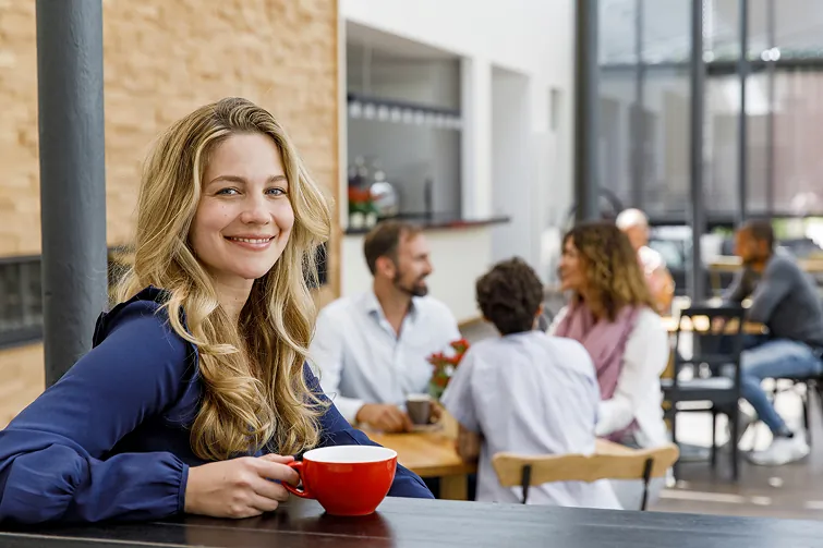 Person sitzt mit einem Café in der Küche, da sie Teilzeit hat.