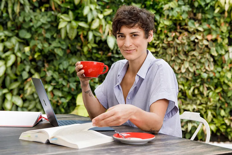 Person sitzt mit ihrem Kaffee draußen Person sitzt mit ihrem Kaffee draußen