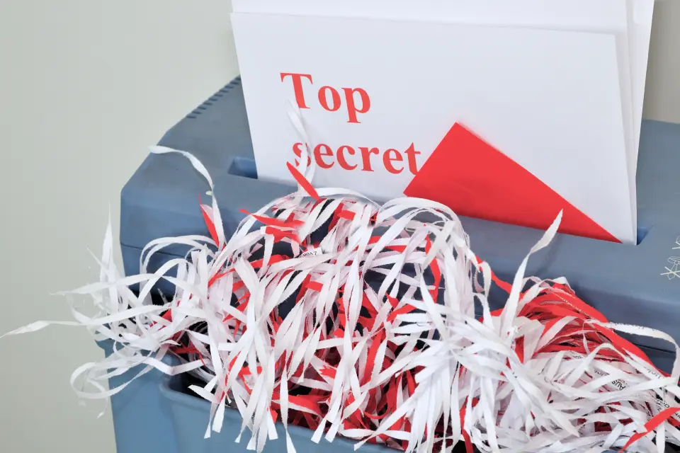 Dokument mit Aufschrift ‚Top Secret‘ in einem Aktenvernichter – Symbol für die Vernichtung verspäteter Briefwahlumschläge bei der Betriebsratswahl. Dokument mit Aufschrift ‚Top Secret‘ in einem Aktenvernichter – Symbol für die Vernichtung verspäteter Briefwahlumschläge bei der Betriebsratswahl.