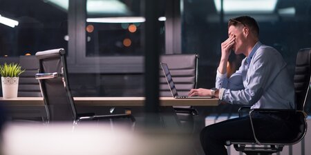 Ein Mann sitzt vor einem Laptop und arbeitet Ein Mann sitzt vor einem Laptop und arbeitet