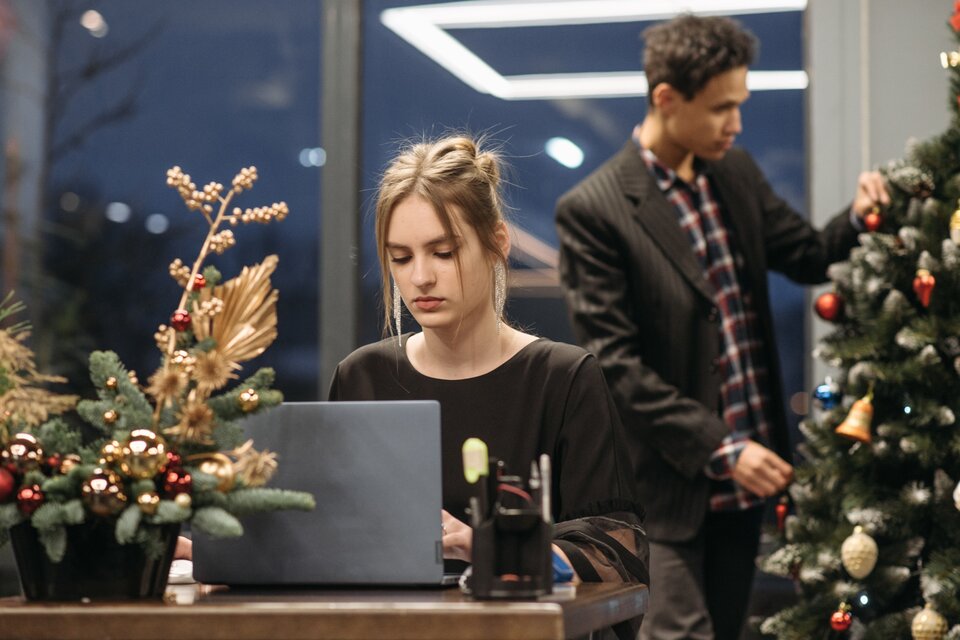 Frau sitzt am Laptop vor einem Weihnachtsbaum Frau sitzt am Laptop vor einem Weihnachtsbaum