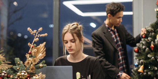 Frau sitzt am Laptop vor einem Weihnachtsbaum