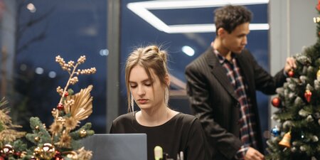 Frau sitzt am Laptop vor einem Weihnachtsbaum