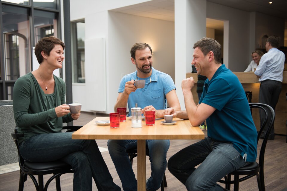 Drei Kollegen unterhalten sich und trinken einen Kaffee Drei Kollegen unterhalten sich und trinken einen Kaffee