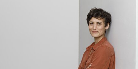 Eine Frau steht vor einer grauen Wand Eine Frau steht vor einer grauen Wand