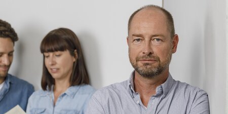 Ein Mann steht vor einer grauen Wand Ein Mann steht vor einer grauen Wand