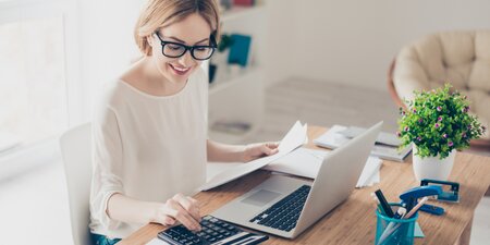 Eine Frau arbeitet und tippt zahlen in einen Taschenrechner