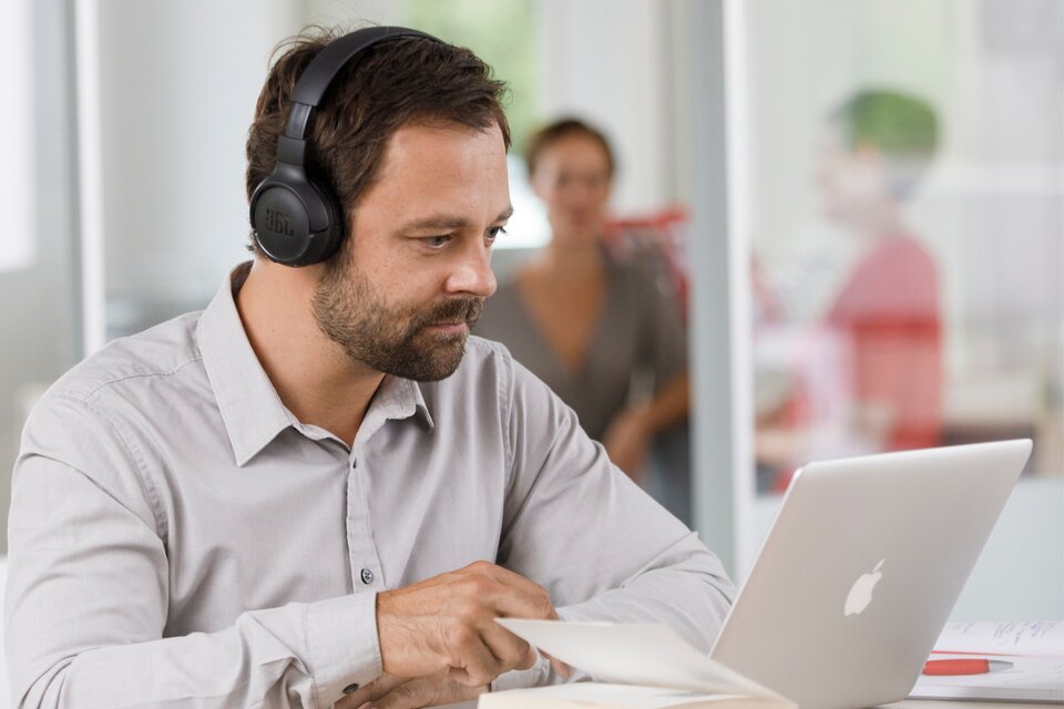 Ein Mann sitzt vor einem Laptop und arbeitet Ein Mann sitzt vor einem Laptop und arbeitet