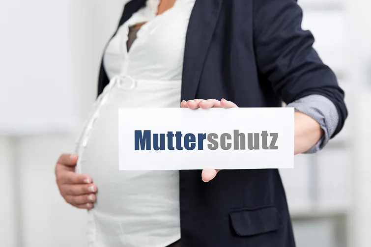 Person ist schwanger und hat ein Plakat in der Hand mit dem Aufdruck Mutterschutz
