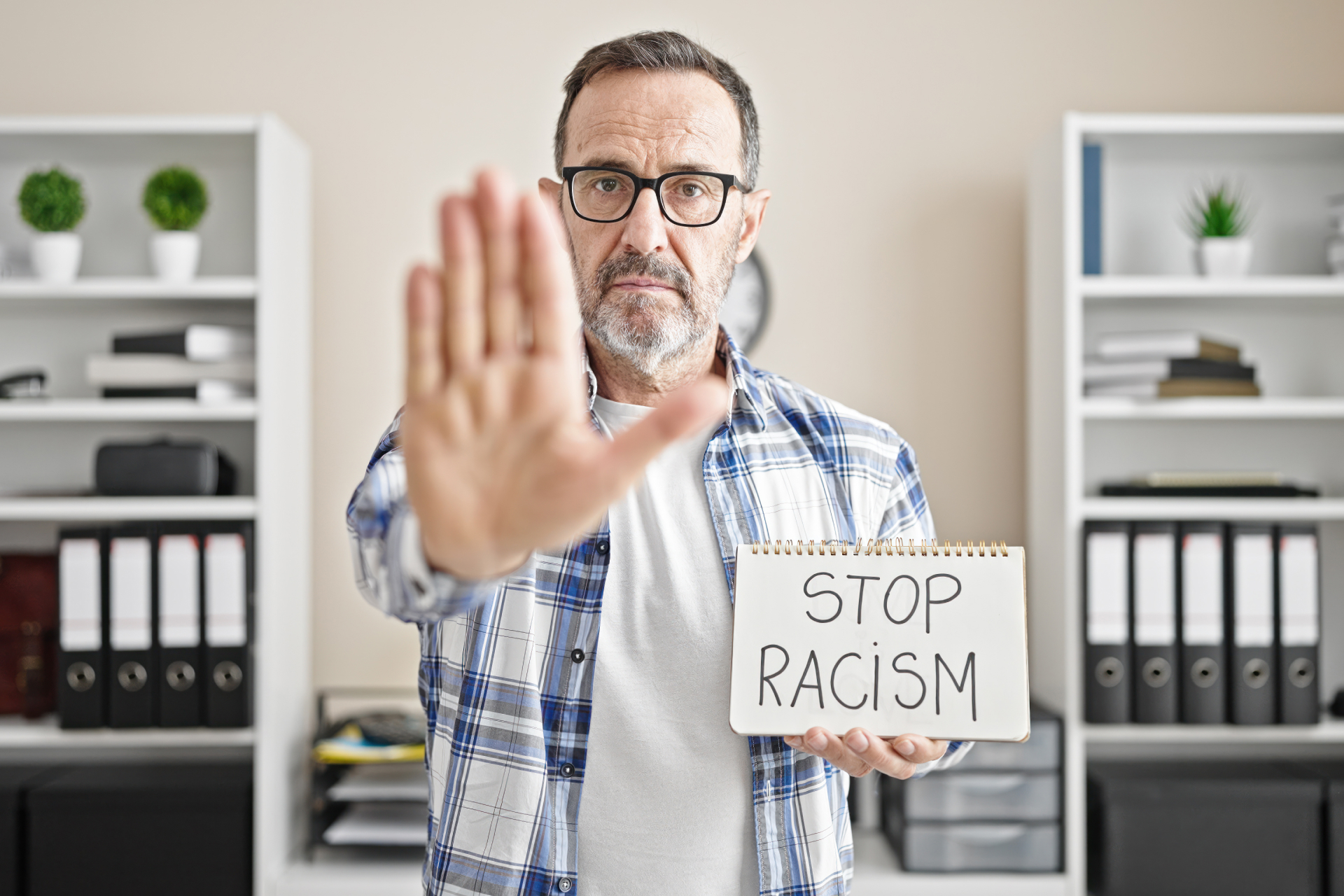 Mann trägt ein Schild mit "Stop Racism"