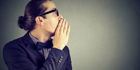Ein Mann hält sich die Hand vor den Mund und flüstert das Hinweisgeberschutzgesetz Ein Mann hält sich die Hand vor den Mund und flüstert das Hinweisgeberschutzgesetz