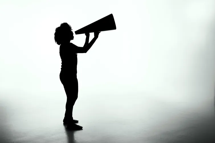 Eine Frau ruft durch ein Megaphone, um die JAV in der Öffentlichkeitsarbeit bekannt zu machen. Eine Frau ruft durch ein Megaphone, um die JAV in der Öffentlichkeitsarbeit bekannt zu machen.