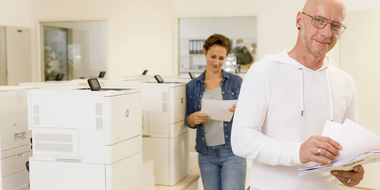 Person entnimmt dem Drucker ein Blatt Papier Person entnimmt dem Drucker ein Blatt Papier