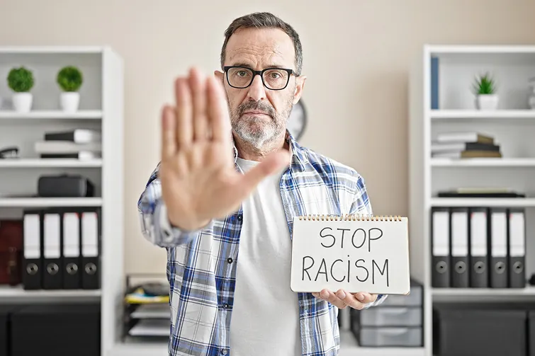 Mann trägt ein Schild mit "Stop Racism" Mann trägt ein Schild mit "Stop Racism"