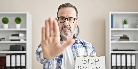 Mann trägt ein Schild mit "Stop Racism" Mann trägt ein Schild mit "Stop Racism"